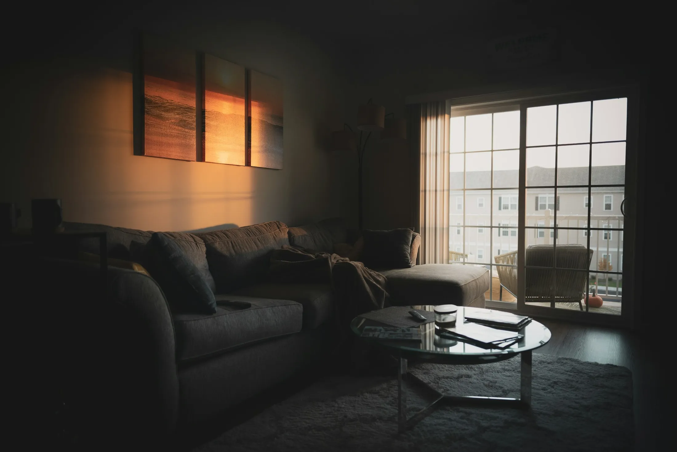 A dark living room with warm window light and a low sofa