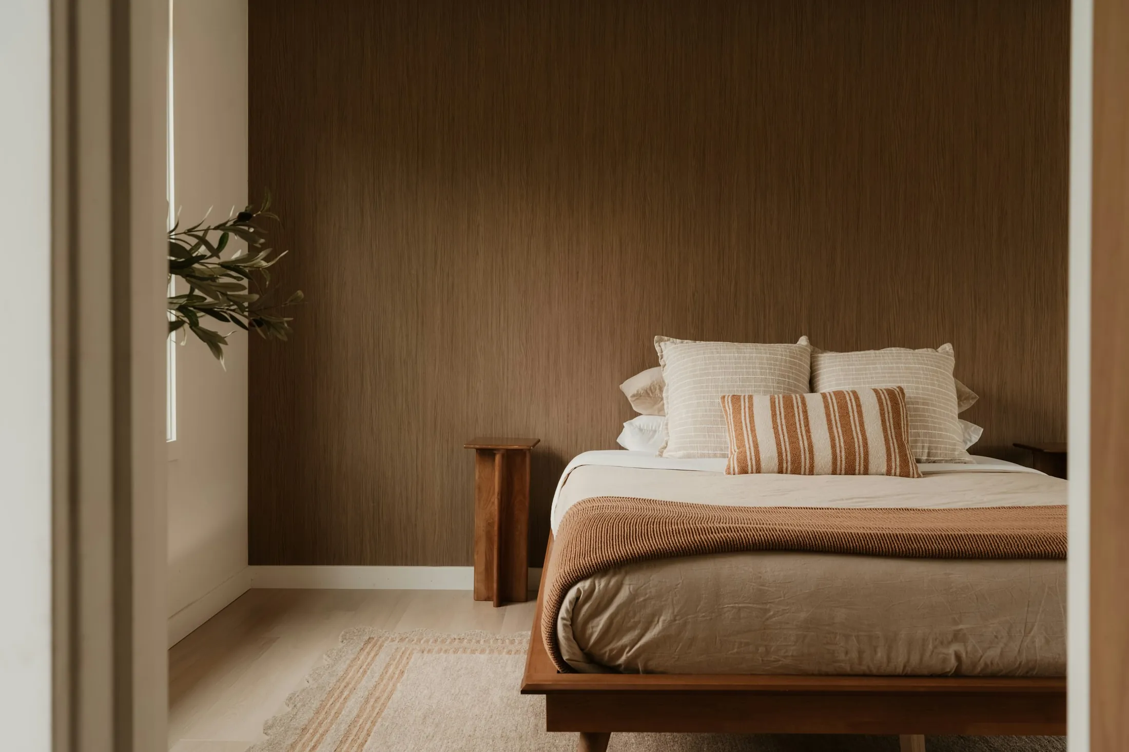 A bedroom with warm timber wall panelling and a low bed