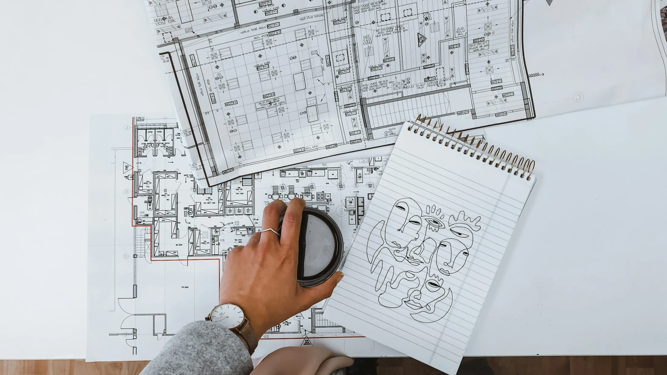 Architectural floor plans on a desk with a notebook